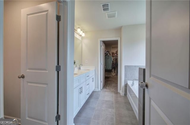 bathroom with a relaxing tiled tub, tile patterned floors, and vanity