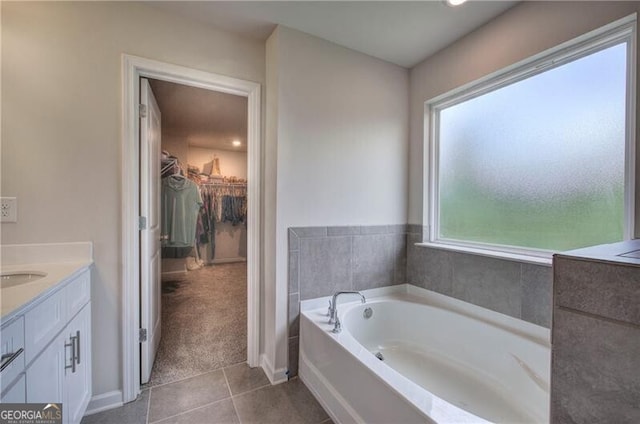 bathroom with a tub to relax in, tile patterned floors, and vanity