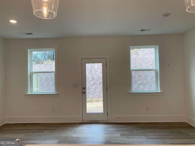 doorway with an inviting chandelier, light wood-type flooring, and a wealth of natural light