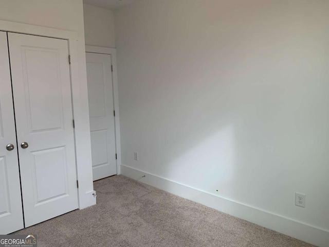 unfurnished bedroom featuring light colored carpet and a closet