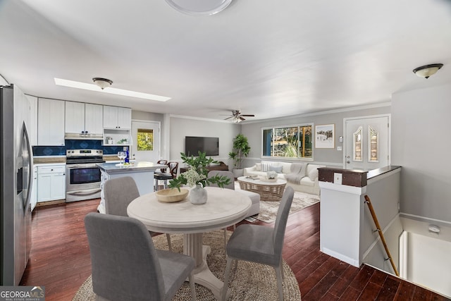 dining area featuring ornamental molding, dark wood-type flooring, ceiling fan, and a skylight