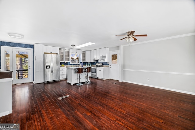 kitchen featuring a breakfast bar area, white cabinetry, a center island, dark hardwood / wood-style flooring, and stainless steel appliances