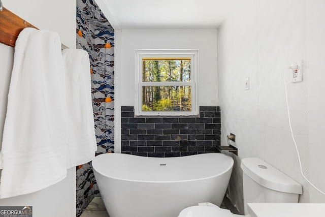 bathroom with a tub, tile walls, and toilet