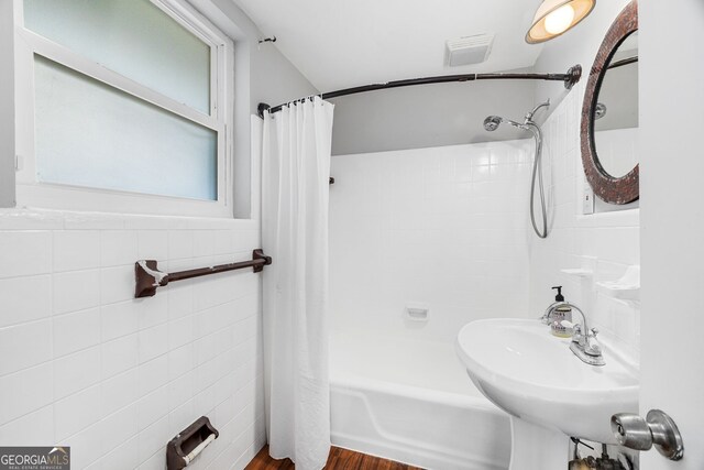 bathroom featuring shower / tub combo with curtain, sink, and tile walls