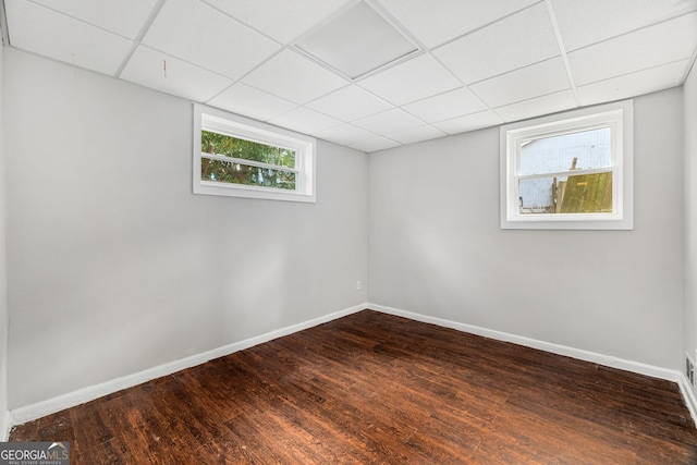 empty room with dark hardwood / wood-style floors and a drop ceiling