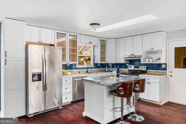 kitchen with stainless steel appliances, white cabinetry, a kitchen island, and sink