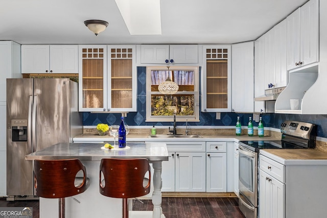 kitchen featuring sink, stainless steel counters, white cabinetry, hanging light fixtures, and stainless steel appliances