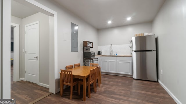 dining room with dark wood-type flooring, electric panel, and sink