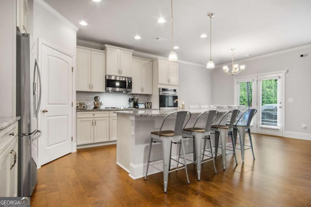 kitchen featuring a center island with sink, light stone countertops, white cabinets, and appliances with stainless steel finishes