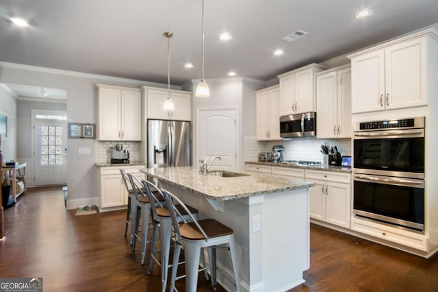 kitchen with white cabinetry, appliances with stainless steel finishes, sink, and a center island with sink