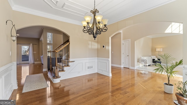 entrance foyer with crown molding, a chandelier, and hardwood / wood-style flooring