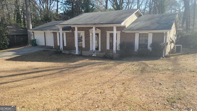 view of front of property featuring a garage, central AC unit, and a front lawn