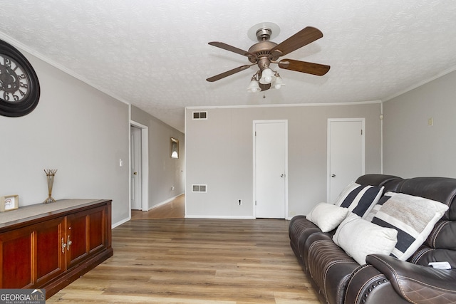 living room featuring ceiling fan, crown molding, a textured ceiling, and light hardwood / wood-style flooring