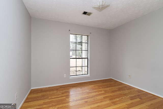 empty room with a textured ceiling and light wood-type flooring