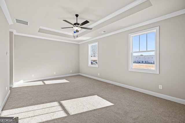 empty room with a tray ceiling, ornamental molding, ceiling fan, and carpet flooring