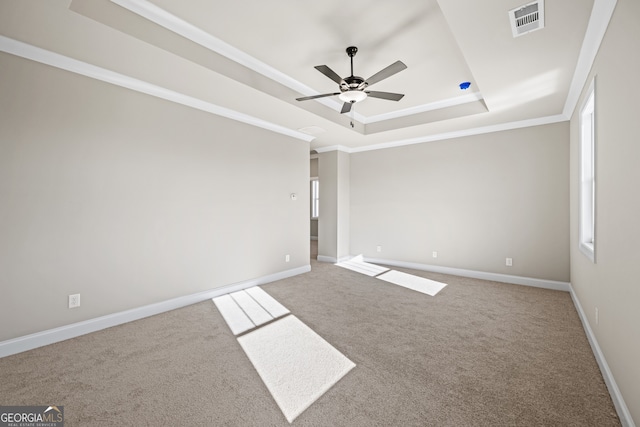 carpeted spare room featuring crown molding, ceiling fan, and a raised ceiling