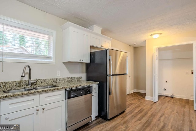 kitchen with white cabinetry, appliances with stainless steel finishes, sink, and light stone counters