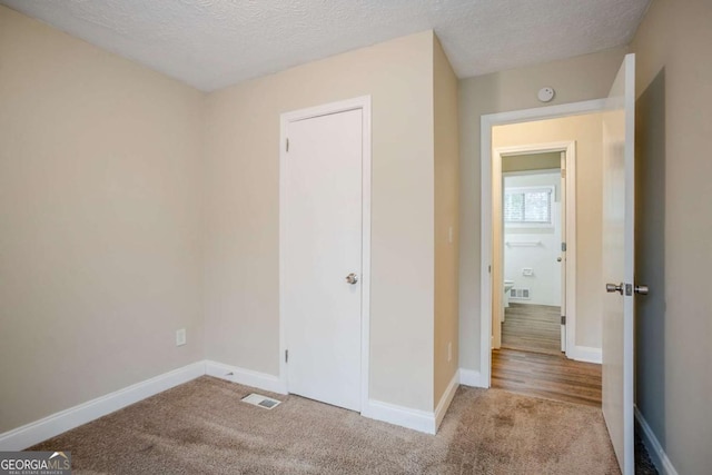 unfurnished bedroom with light carpet and a textured ceiling