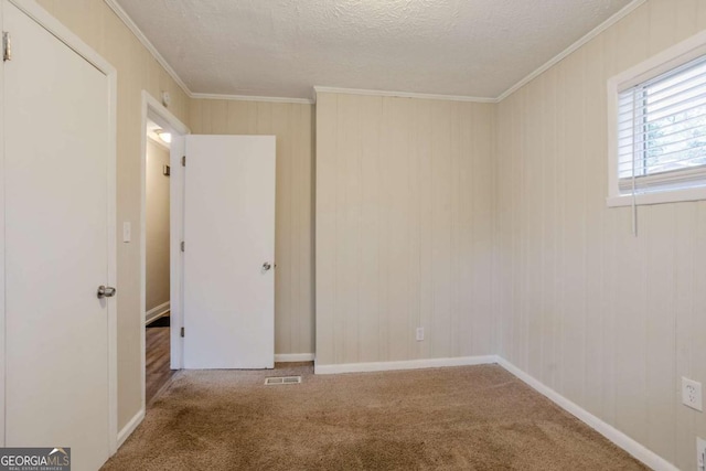 carpeted empty room with ornamental molding and a textured ceiling