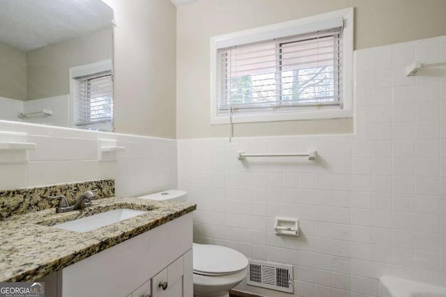 bathroom featuring vanity, toilet, and tile walls