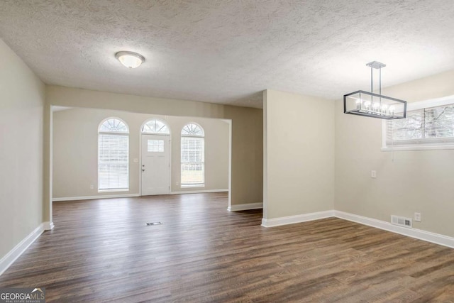 entrance foyer featuring dark hardwood / wood-style flooring, a textured ceiling, and a chandelier