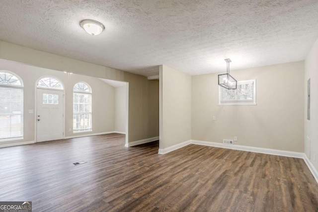 entrance foyer featuring dark wood-type flooring, an inviting chandelier, and a textured ceiling