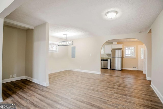 unfurnished living room with hardwood / wood-style flooring, electric panel, and a textured ceiling