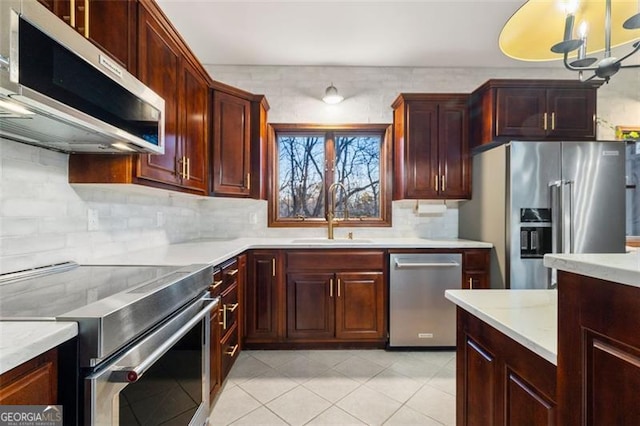 kitchen with stainless steel appliances, sink, light tile patterned floors, and decorative backsplash