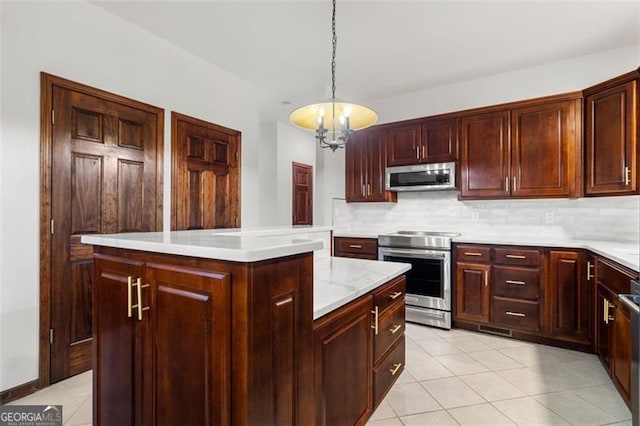 kitchen featuring decorative light fixtures, a kitchen island, a notable chandelier, stainless steel appliances, and backsplash