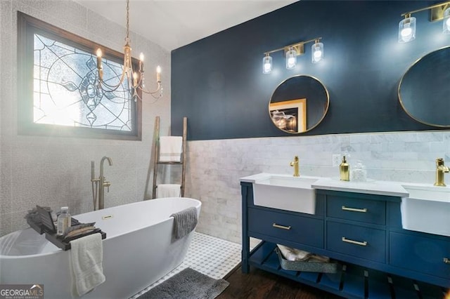 bathroom featuring hardwood / wood-style flooring, tile walls, vanity, a notable chandelier, and a bathing tub