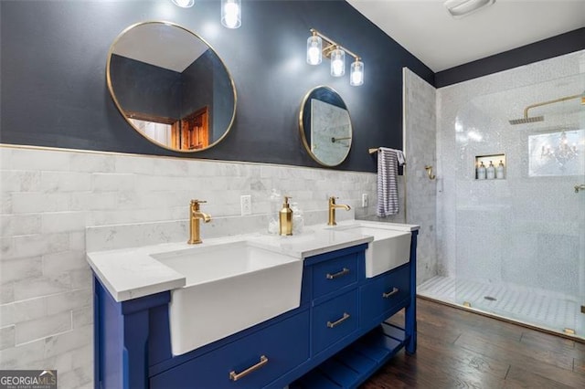 bathroom featuring wood-type flooring, tiled shower, tile walls, and vanity