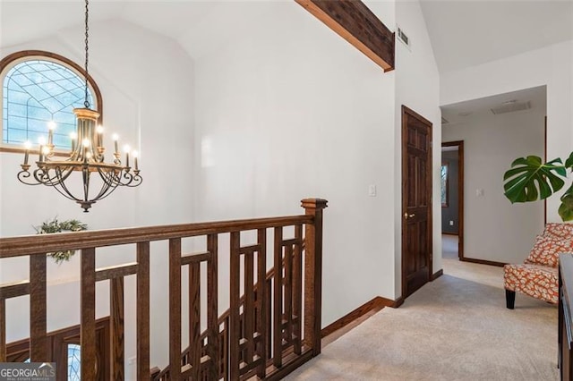 corridor with lofted ceiling, light carpet, and an inviting chandelier