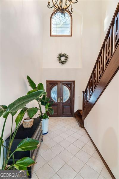 entrance foyer with a notable chandelier, light tile patterned flooring, and a high ceiling