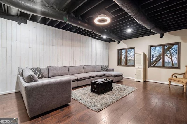 living room featuring wooden walls, dark hardwood / wood-style floors, and beamed ceiling