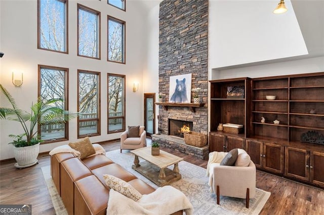 living room with wood-type flooring, a towering ceiling, and a fireplace