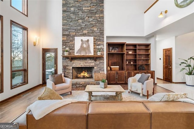 living room with a fireplace, light hardwood / wood-style floors, and a high ceiling