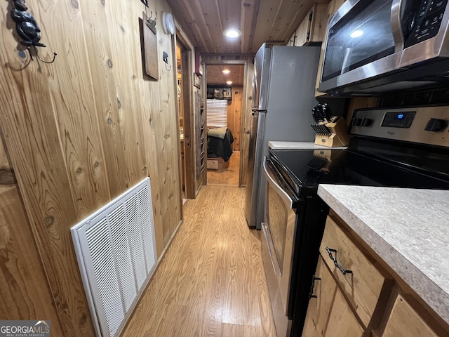 kitchen with light hardwood / wood-style flooring, stainless steel appliances, wooden ceiling, and wood walls