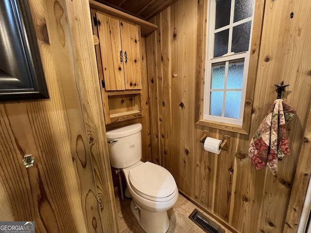 bathroom featuring toilet and wood walls