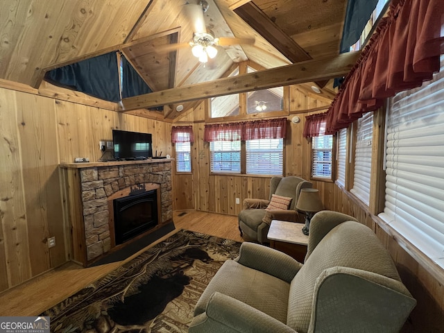 living room featuring a stone fireplace, vaulted ceiling with beams, wood ceiling, wood walls, and wood-type flooring