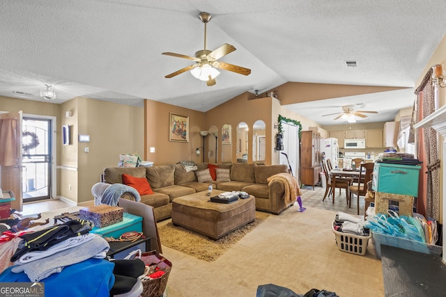 living room with ceiling fan, lofted ceiling, light colored carpet, and a textured ceiling