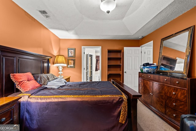 carpeted bedroom with a raised ceiling and a textured ceiling