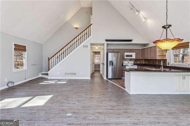 kitchen with dark wood-type flooring, white appliances, a healthy amount of sunlight, and decorative light fixtures