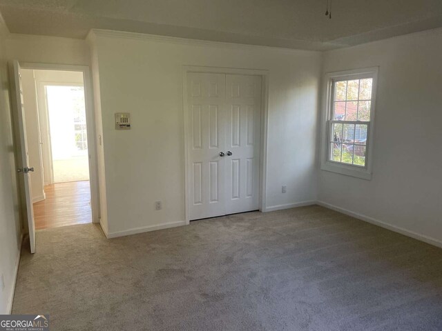 unfurnished bedroom with light colored carpet and a closet