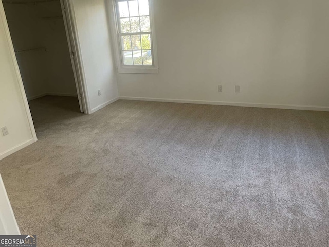 unfurnished bedroom with a walk in closet and carpet