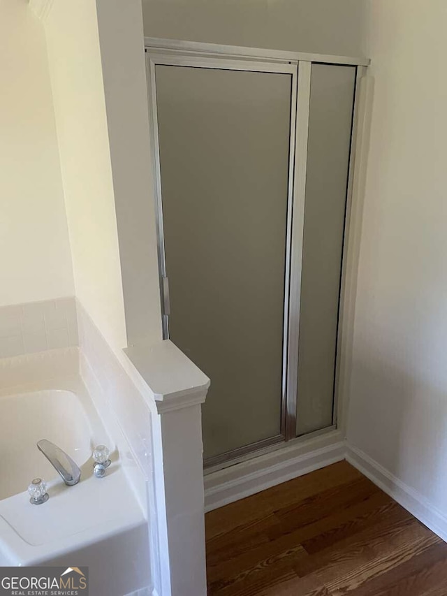 bathroom featuring wood-type flooring and shower with separate bathtub