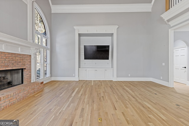 unfurnished living room with ornamental molding, a healthy amount of sunlight, a fireplace, and light hardwood / wood-style floors