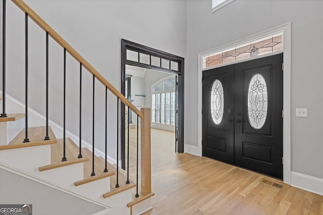 foyer entrance with a towering ceiling and light hardwood / wood-style floors