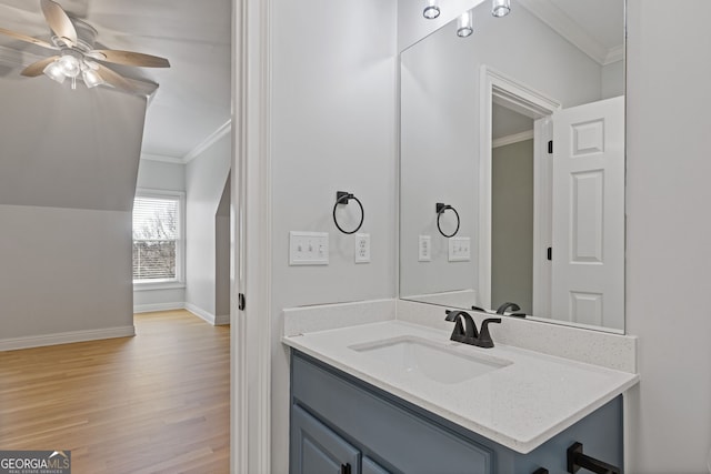 bathroom with crown molding, ceiling fan, vanity, and wood-type flooring