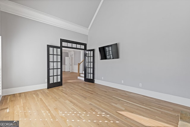 unfurnished room featuring french doors, crown molding, light hardwood / wood-style floors, and high vaulted ceiling