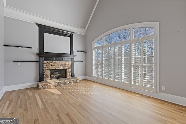 unfurnished living room with a healthy amount of sunlight, ornamental molding, a fireplace, and light hardwood / wood-style floors